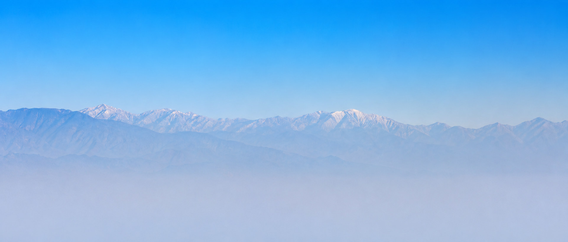 Mountain range behind a Los Angeles skyline and palm trees